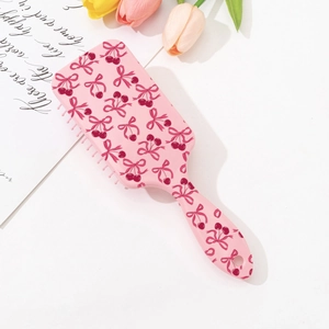 Detailed top view of pink hairbrush with cherry bow print and soft massage bristles