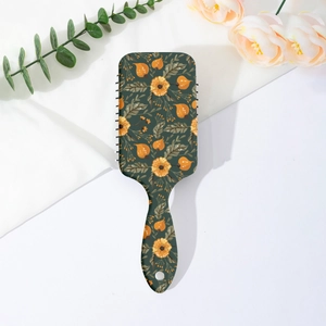 Close-up of floral paddle brush with orange daisies on dark green handle and back