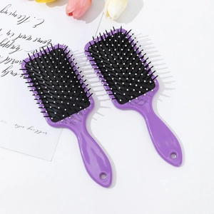 Detail of two purple hair brushes with massage bristles and hang holes on white background