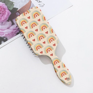 Dettaglio della spazzola rettangolare con stampa di arcobaleni e cuori su base beige