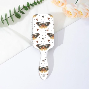 Détail d'une brosse à cheveux avec motif papillon, pois noirs et poignée ergonomique