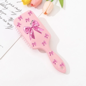 Brosse à cheveux massante rose avec motifs nœuds scintillants et poignée ergonomique