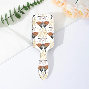 Détail de l'imprimé papillon et fleurs sur une brosse à cheveux plate pour le massage