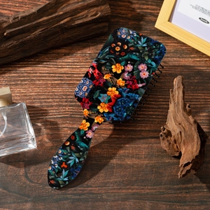 Detail of vintage floral hair brush with cushion on a rustic wooden table setting