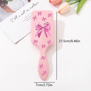 Brosse à cheveux rose avec motifs nœuds, picots massants et dimensions 21,5cm x 7cm