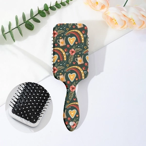 Detail view of air cushion hairbrush with floral prints and massaging bristles on a desk
