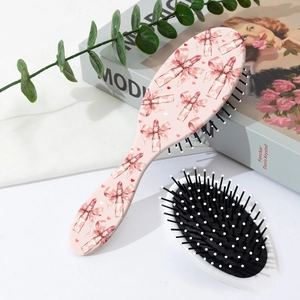Dettaglio della spazzola per capelli rosa con fiocchi e cuori su un tavolo bianco