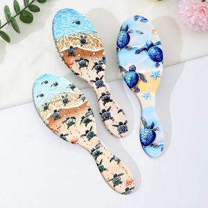 Three sea turtle printed hair brushes on a white background with floral decoration