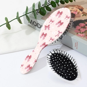 Vista dettagliata della spazzola per capelli rosa con fiocchi e setole a punta bianca