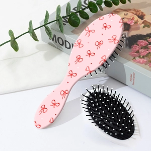 Dettaglio spazzola per capelli rosa con fiocchi carini e setole a cuscinetto massaggianti