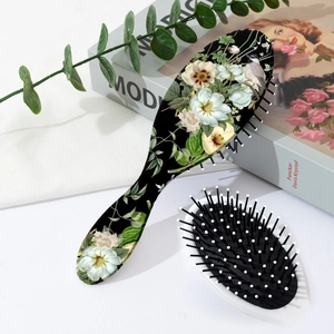 Detailed back view of vintage floral and bird pattern on an oval massage hairbrush