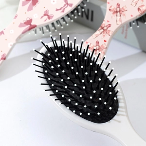 Spazzola per capelli con fiocco rosa, cuscino per massaggio e manico bianco