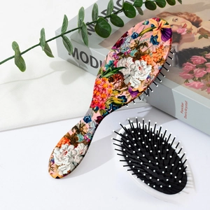 Top view of floral cushion hairbrush with massage bristles on a white aesthetic background