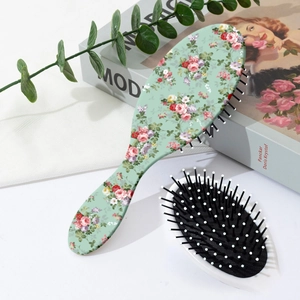Vue détaillée d'une brosse à cheveux fleurie avec coussin d'air et picots massants