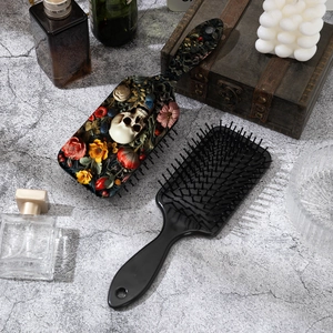 Gothic skull and floral rose pattern air cushion hair brush set on a stone surface