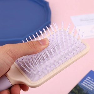 Detail shot of macaron cushion hairbrush showing flexible resilience and soft massage bristles