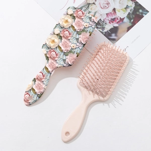 Détail de la brosse à cheveux à fleurs 3D et d'une brosse plate rose minimaliste