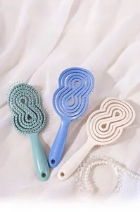 Trois brosses à cheveux massantes ajourées aux tons pastels sur un tissu doux