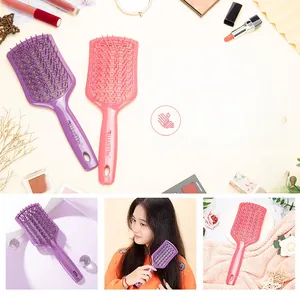 Detail of hollow curved massage hairbrush with ergonomic handle in purple and pink