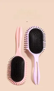 Dettaglio di spazzole per capelli massaggianti rosa e viola con manici ergonomici cavi