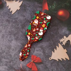 Detail view of red Christmas paddle brush with Santa and tree patterns in festive setting