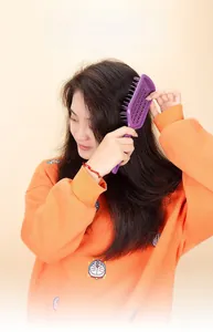 Macro detail of the purple massage hairbrush showing the cushion bristles and handle