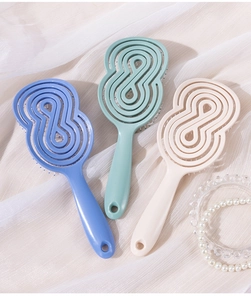 Trois brosses à cheveux spirales aérées présentées sur un tissu blanc doux plissé