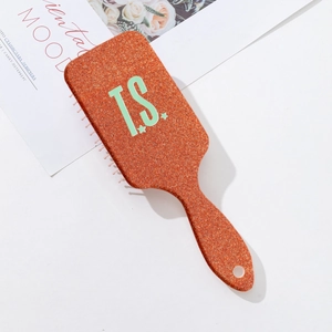 Orange rectangular air cushion massage hairbrush with T.S. print on a white background