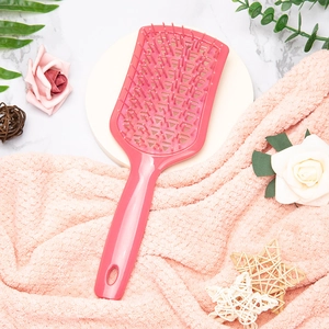 Pink hollow-out curved vented hairbrush for wet and dry detangling on marble background
