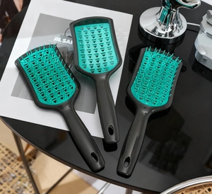 Detail of ergonomic vented hair brush with mint green bristles and black handle