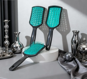 Three vented hair brushes with teal bristles and grey handles on a white platform