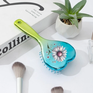 Gros plan d'une brosse à cheveux en cœur avec dégradé bleu-vert et motif de marguerites