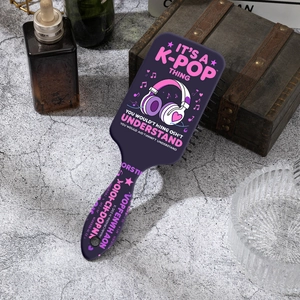 Detail of purple K-pop theme air cushion hairbrush with musical print on stone table