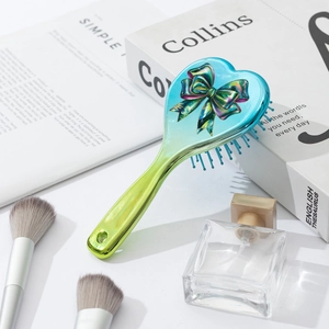 Detail of heart-shaped gradient paddle brush with bow pattern and ergonomic handle
