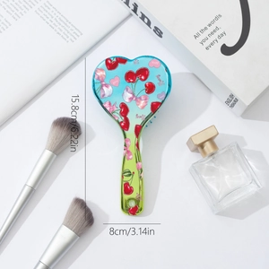 Heart-shaped cherry bow hairbrush with blue-green gradient on a white surface
