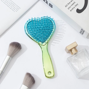 Macro detail of heart-shaped massage hairbrush with golden metallic handle and blue bristles