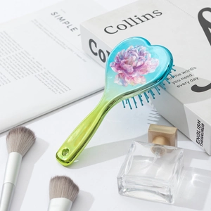 Detail of gradient heart-shaped air cushion hairbrush with purple floral print