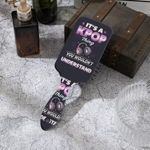Detail of k-pop themed air cushion massage hairbrush on a textured stone surface