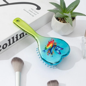 Macro detail of heart-shaped air cushion hairbrush with rainbow butterfly print on blue back