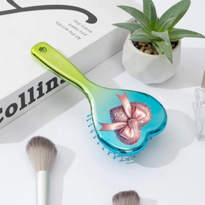 Detail of heart-shaped hair brush with gradient finish and pink bow on white desk