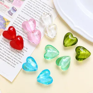 Nahaufnahme bunter herzförmiger Glasperlen für DIY-Schmuck auf einer Vintage-Zeitung