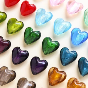 Vista macro di perline di vetro colorate a cuore con glitter per gioielli fai da te