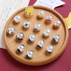 Macro shot of Halloween ghost and pumpkin beads in a wooden tray for DIY jewelry making