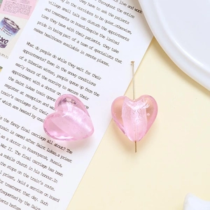 Dettaglio di perline in vetro a cuore rosa e spilla dorata per gioielli fai-da-te