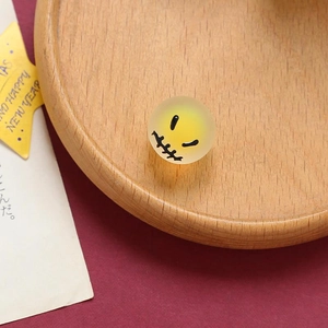 Macro shot of yellow frosted bead with stitched smile face for Halloween DIY jewelry