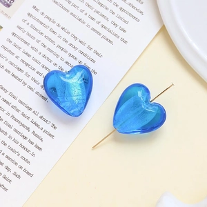 Dettaglio macro di perle di vetro a cuore blu con bolle su una pagina di rivista