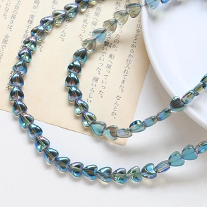 Macro detail of iridescent heart-shaped glass beads for DIY jewelry with rainbow metallic finish