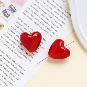 Macro di orecchini a cuore in vetro rosso su una rivista per design di gioielli DIY