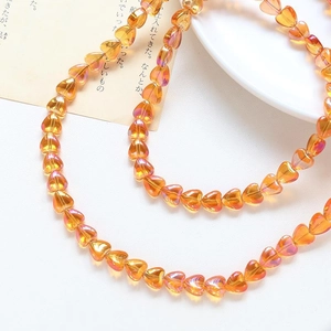 Close-up of translucent orange heart glass beads for DIY jewelry making and necklaces