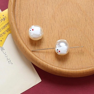 Detailed view of Halloween ghost pearl beads with a needle through the craft hole